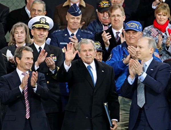 President Bush surround by veterans and veterans families.  At left is Intrepid Museum co-chairman Richard Santulli, and co-chairman Charles de Gunzberg is at right.